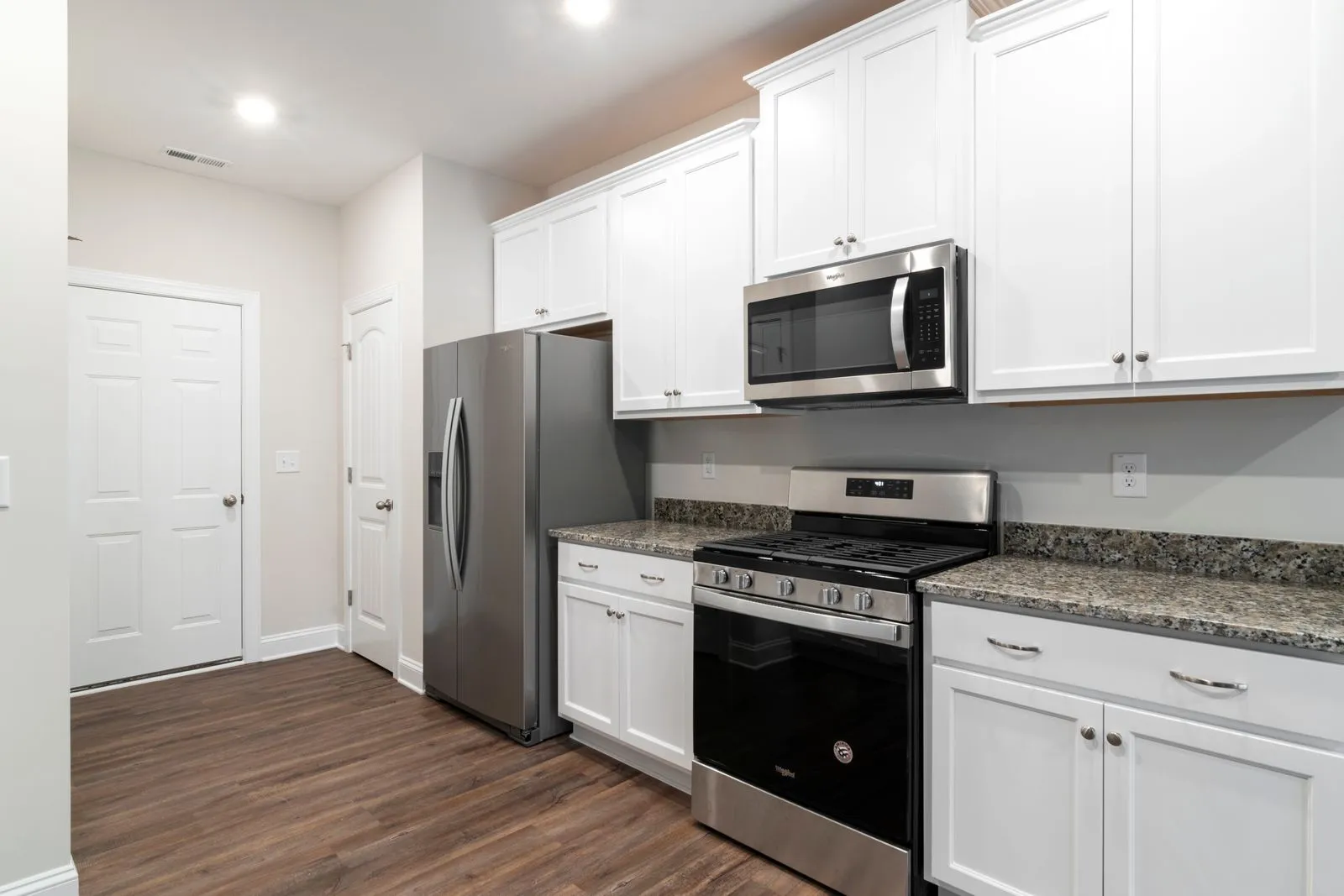 A kitchen with an over-the-range microwave, range and refrigerator fitted