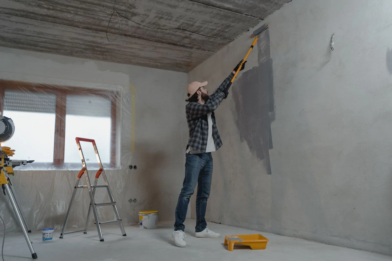 A worker smoothing a bare interior wall during a room renovation