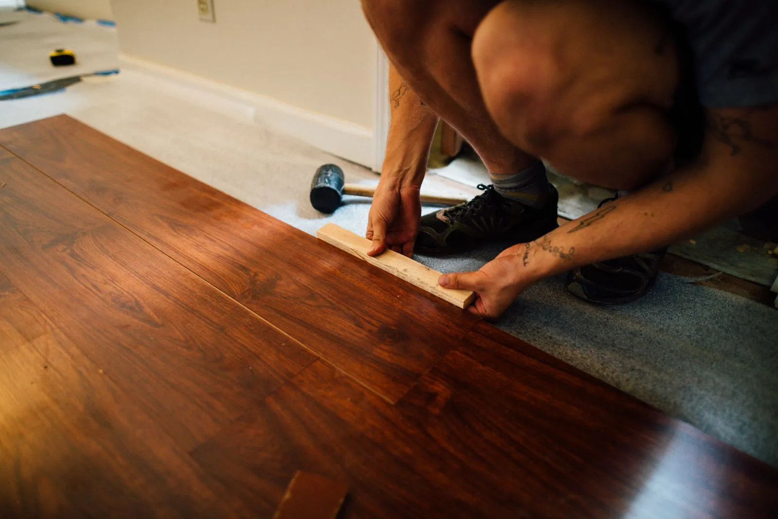 A worker fitting a plank while installing wood flooring