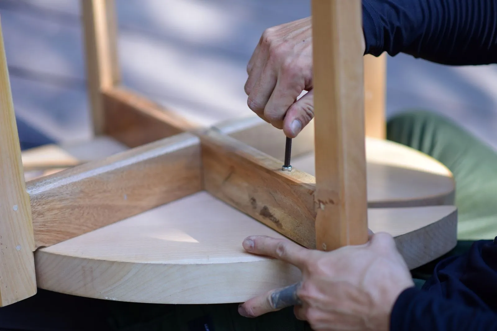 Hands fitting the legs onto a wooden table during assembly
