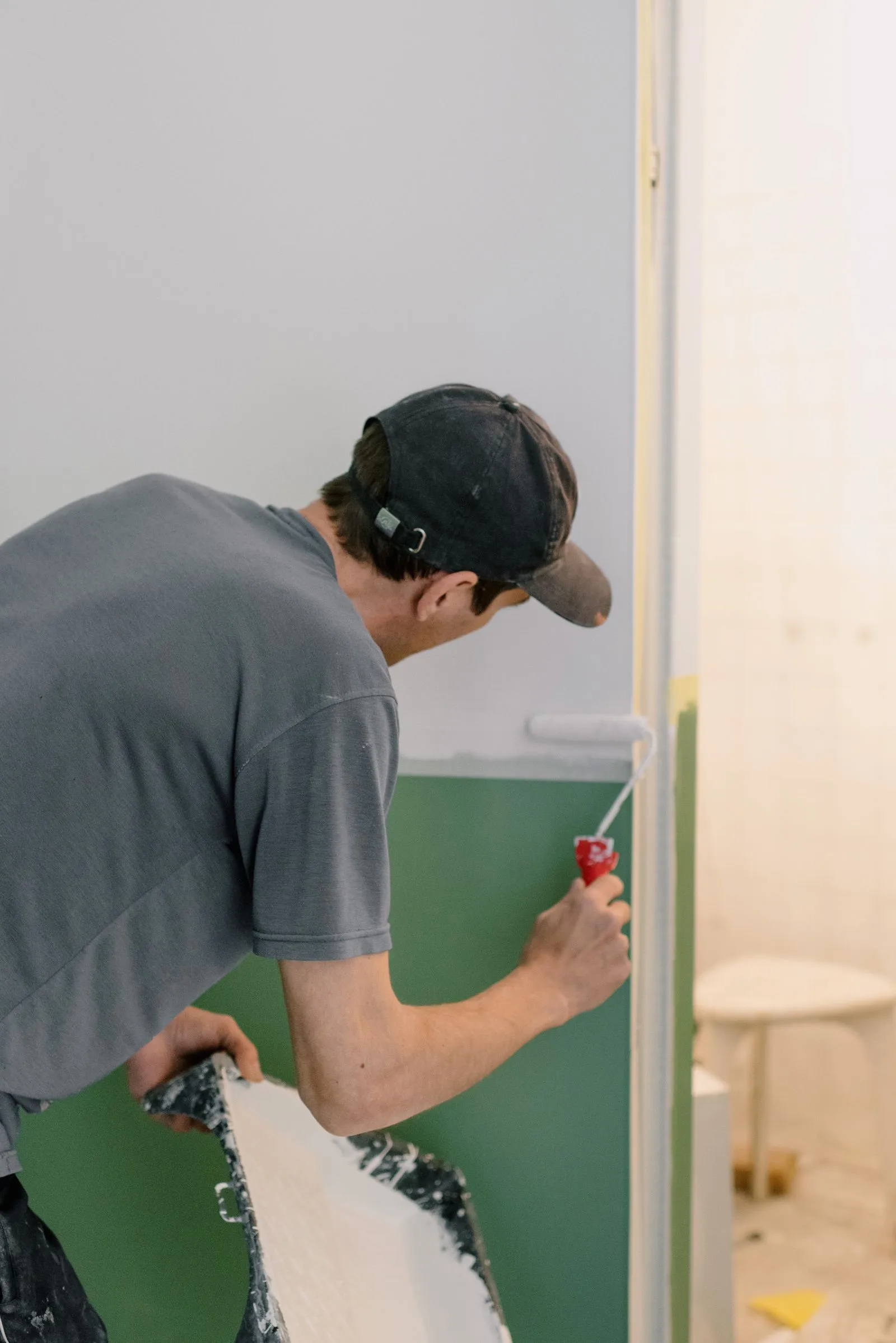 A man rolling fresh paint onto an interior wall